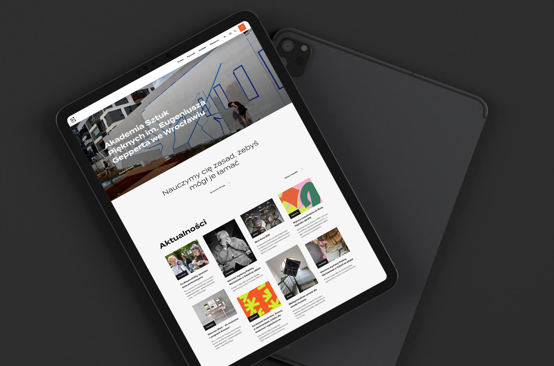Case study ASP Tablet wyświetlający stronę internetową Akademii Sztuk Pięknych im. Eugeniusza Gepperta we Wrocławiu, z widocznym nagłówkiem, hasłem „Nauczymy cię zasad, żebyś mógł je łamać” oraz sekcją aktualności zawierającą miniatury artykułów i wydarzeń.